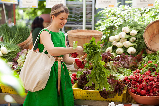Young woman buying fresh organic produce at a local farmer's market.