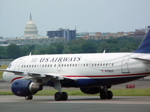 Washington, DC, USA - June 2, 2013: US Airways jet taxiing in front of the US Capital at Ronald Reagan Washington National Airport (IATA: DCA). The airport is located just across the Potomac River from the National Mall, with convenient public transportation to downtown business and government districts.