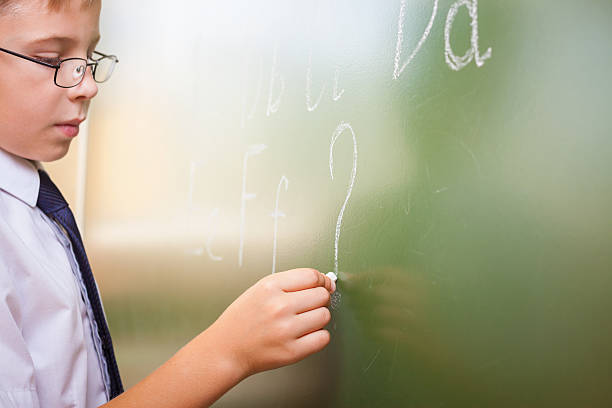 istock School boy writes English alphabet with chalk on blackboard 483346592