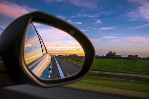 sonnenuntergang auf dem highway (motin blured) - rear view mirror car mirror rear view stock-fotos und bilder