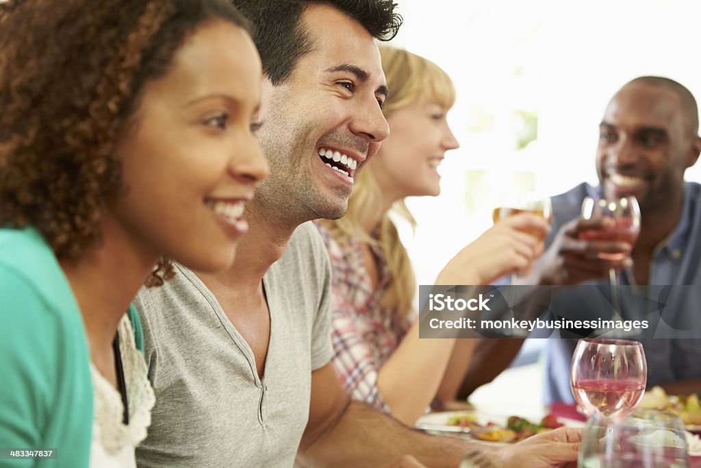 Multiracial friends having fun at a dinner party. Multi Racial Group Of Friends Sitting Around Table Having Dinner Party 20-29 Years Stock Photo