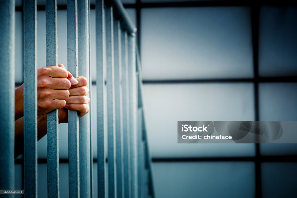 Prisoner A prisoner behind the jail cell bars . Prison Stock Photo