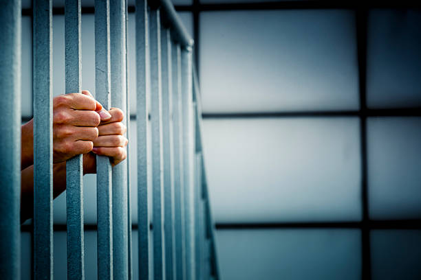 Prisoner A prisoner behind the jail cell bars . cage photos stock pictures, royalty-free photos & images