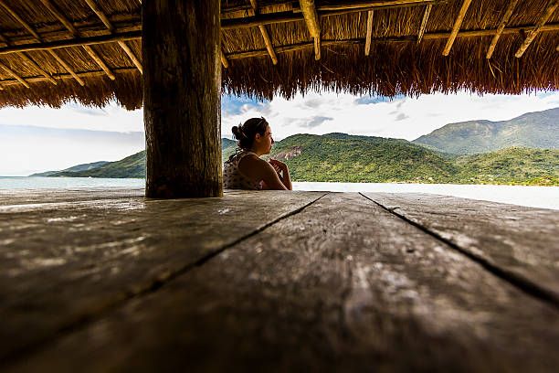istock Woman Relaxing in a Hut Watching the Sea 483364168