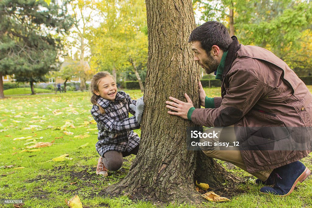 Father and daughter playing in the park Father and daughter playing hide-and-seek in the park Family Stock Photo