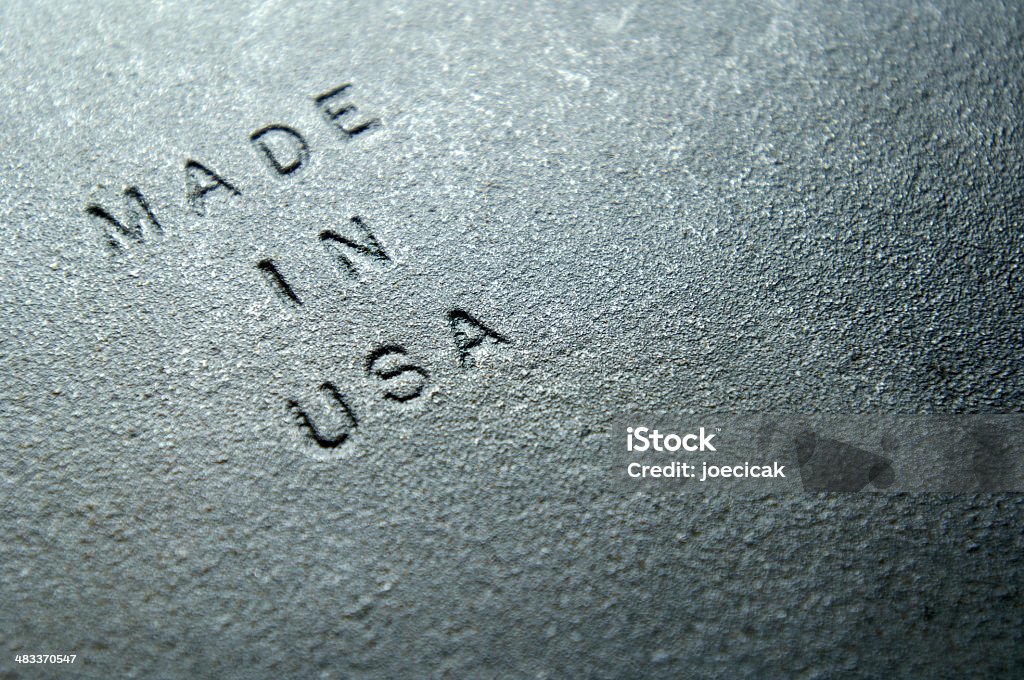 Sand Cast Iron Embossed With MADE IN USA Old plate of rough, gritty, textured, sand-casted iron imprinted with "MADE IN USA." Shot with a shallow depth of field for dramatic emphasis. Perfect background for print piece about jobs, out-sourcing, industry, loss of manufacturing factories and skills. Made in the USA - Short Phrase Stock Photo