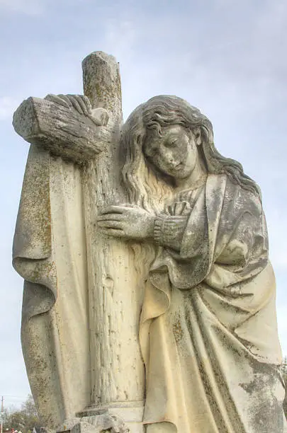 A very old statue is photographed in a very old cemetery.