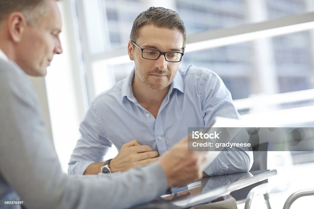 Businessmen with tablet during meeting Two mature businessmen using a digital tablet together during a meeting Customer Stock Photo