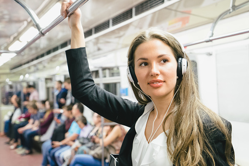 Beautiful woman listening to music from her smartphone while on subway train.