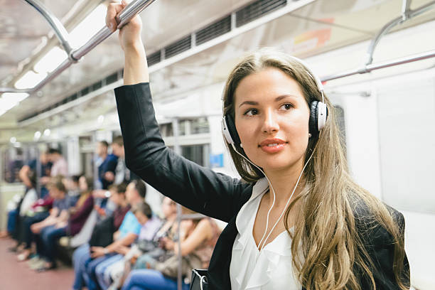 красивая женщина, слушать музыку на ее смартфон на поезд метро - rush hour audio стоковые фото и изображения