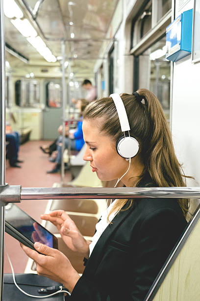 красивая женщина, слушать музыку на ее таблетки в поезде метро - rush hour audio стоковые фото и изображения