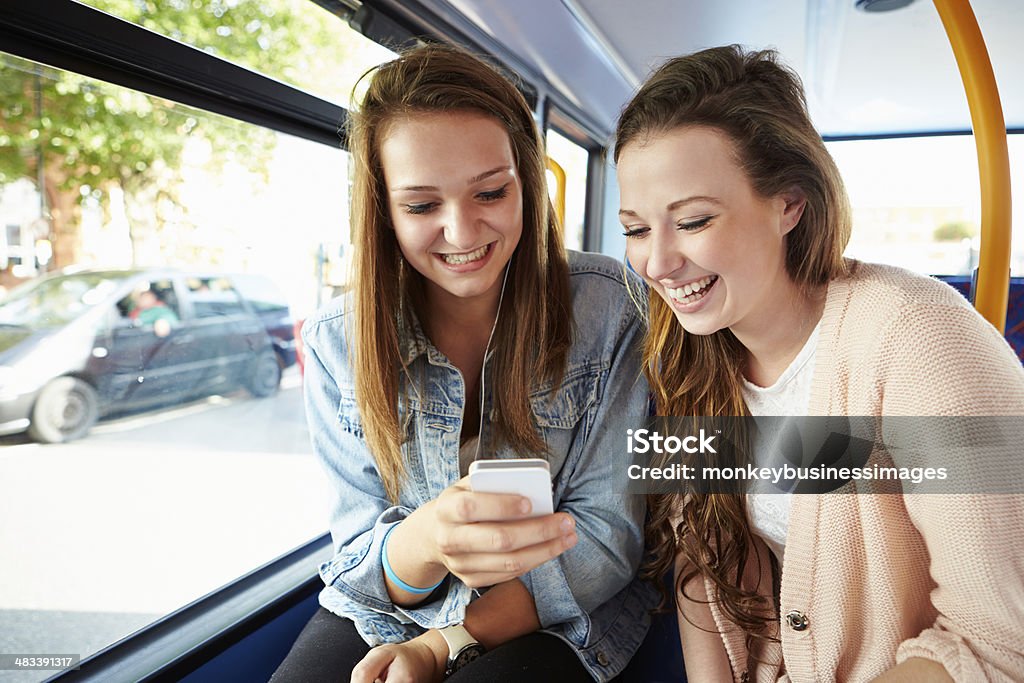 Two Young Women Reading Text Message On Bus Two Young Women Reading Text Message On Bus Before College Bus Stock Photo