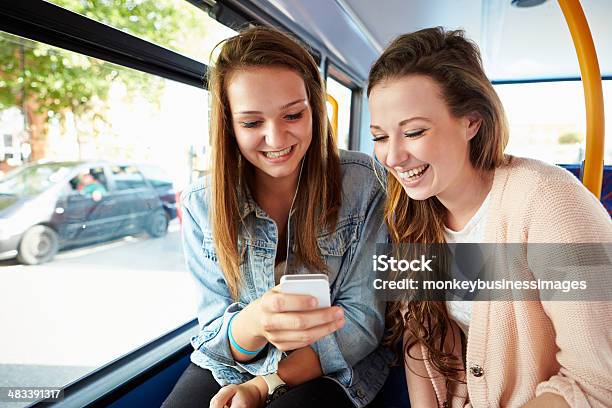 Two Young Women Reading Text Message On Bus Stock Photo - Download Image Now - Bus, Teenager, Teenage Girls