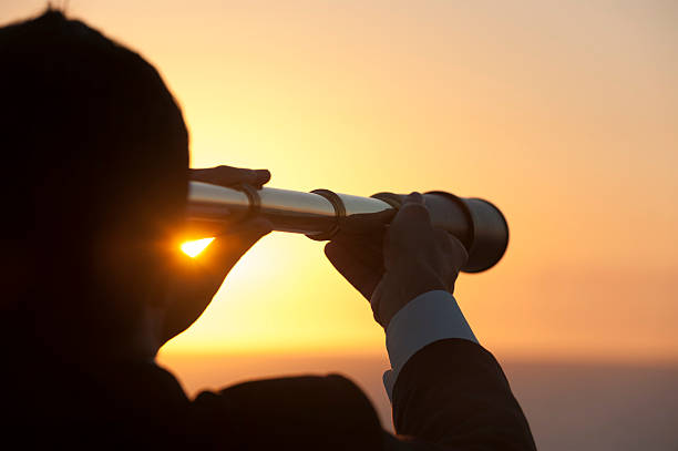 Businessman looking to the future with telescope Businessman looking to the future with telescope at sunriseVision concept. Calm businessman surveys the future.  calculating stock pictures, royalty-free photos & images