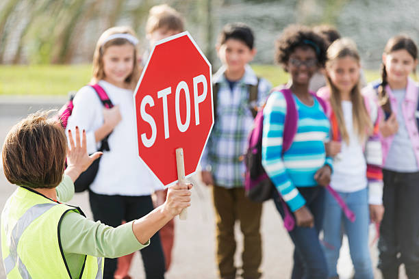 School crossing guard School crossing guard (Hispanic mature woman, 50s) helping children walk across street.  Focus on foreground. crossing sign stock pictures, royalty-free photos & images
