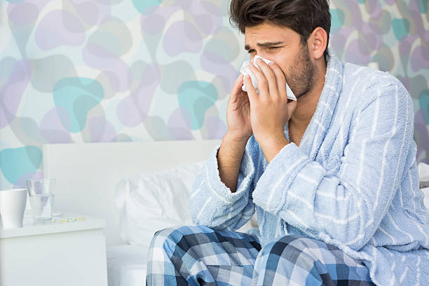 istock Sick man blowing his nose in tissue paper 483397559