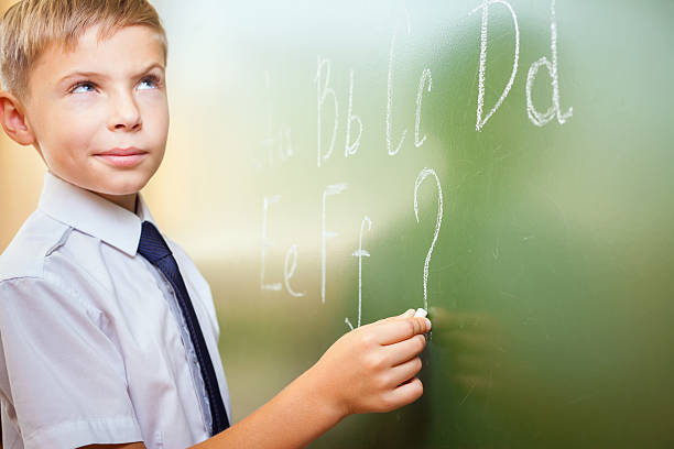 istock School boy writes English alphabet with chalk on blackboard 483405542