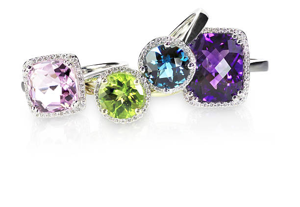 Row of multicolored rainbow diamond halo gemstone rings A stack of beautiful gemstone rings, tourmaline, citrine, topaz, peridot, quartz, amethyst, diamond or other gemstones surrounded by diamonds. Set in silver colored white gold. Multiple carats. Four rings stacked on top of each other isolated on a white background with a reflection. Cushion and brilliant cut with halo rings. ring jewelry stock pictures, royalty-free photos & images