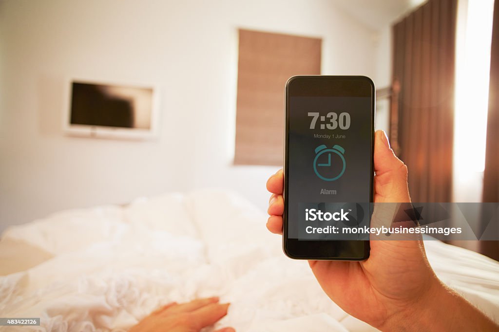 Persona en la cama doble en el teléfono alarma - Foto de stock de Despertador libre de derechos
