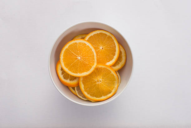 istock orange slices in a white bowl on white fabric background 483426160