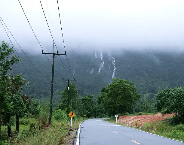Stream of Waterfall lash down. Foggy mountain look cool. foreground is road go straightly to mountain.foggy,