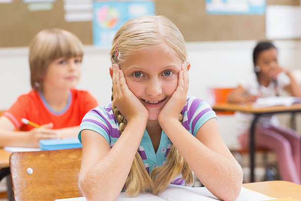 istock Smiling pupil sitting at her desk 483426772
