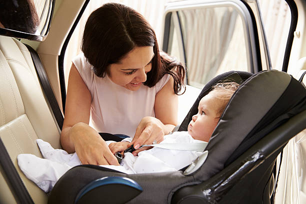 Mother Putting Baby Son Into Car Travel Seat Mother Putting Baby Son Into Car Travel Seat buckle stock pictures, royalty-free photos & images