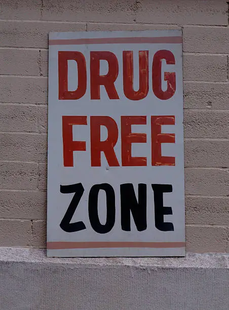 Metallic sign on a wall enforcing a drug free zone