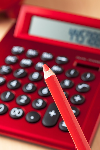 Red calculator, red pencil in foreground