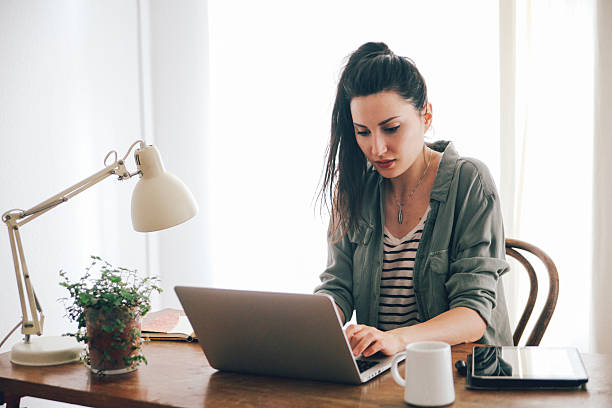 istock young brunette looking at laptop 483436396