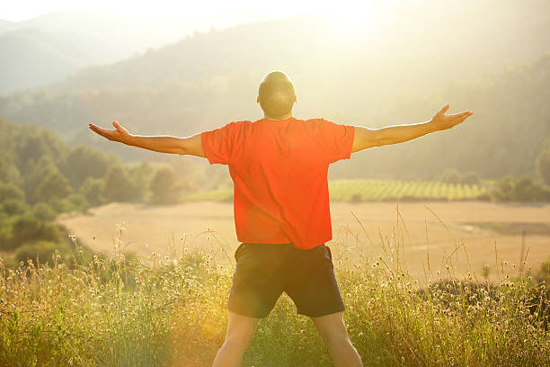 istock Man standing in nature with arms outstretched 483442460
