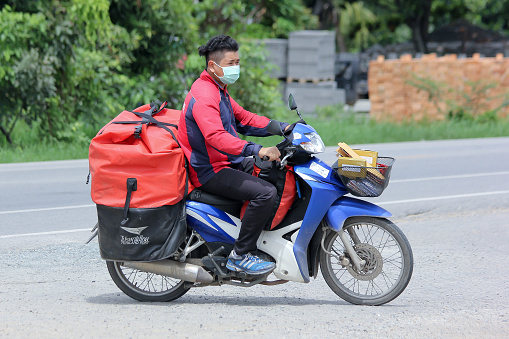 Chiangmai, Thailand -August  6, 2015: An unidentified Postman of Thailand Post. Photo at road no.121 about 8 km from downtown Chiangmai, thailand.