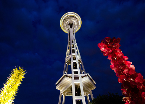 Seattle, WA, USA - June 2, 2014: The Chihuly Garden and Glass exhibit illuminates the night as the world famous Space Needle towers above. The exhibit in the Seattle Center showcases the artwork of Dale Chihuly and opened in 2012.