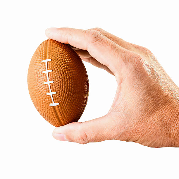 istock hand holding miniaturized rubber rugby ball over white background 483447022