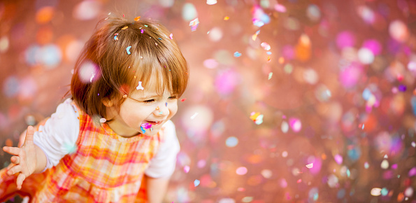 Portrait Of A Happy Little Girl With Confetti Falling Around Her
