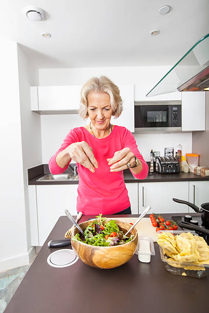 istock Senior woman preparing salad at kitchen counter 483447799