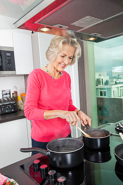 istock Smiling senior woman preparing food at kitchen counter 483447859