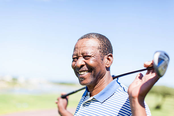 afrique senior golfeur tenant son club avec un grand sourire. - homme 65 ans photos et images de collection