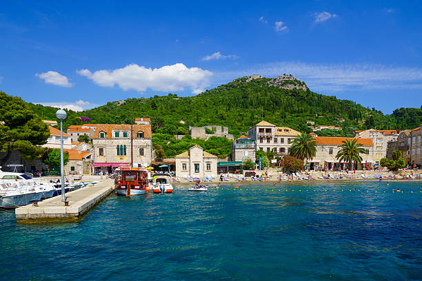 Lopud Beach and Port Lopud, Croatia - June 27, 2015: Scene of the fishing port and the beach, with boats, locals and tourists, in the village Lopud, Lopud Island, one of the Elaphiti Islands, Croatia dubrovnik lopud stock pictures, royalty-free photos & images