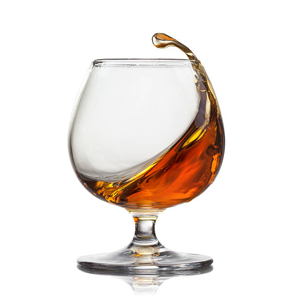 Splash of cognac in glass isolated on white background Splash of whiskey with ice in glass isolated on white background cognac region photos stock pictures, royalty-free photos & images