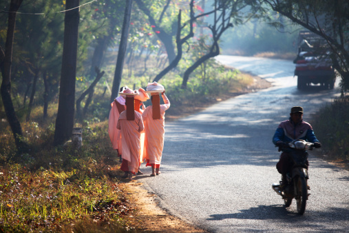 Pyi Oo Lwin,Burma/Myanmar - January 14, 2014: Group of young nuns and traffic in the  early morning light in  Burma/Myanmar. The nuns are walking from house to house  asking for food or other donations.