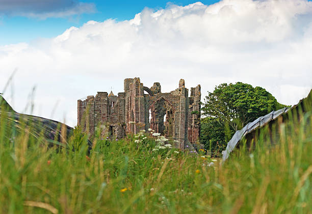 Lindisfarne Priory Lindisfarne Priory ruins seen between 2 'boat huts' -wooden huts in the shape of half a boat hull turned upside down. Focus is on the priory with foreground thrown out of focus. lindisfarne monastery stock pictures, royalty-free photos & images
