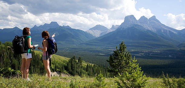 Mountain Hikers Female backpackers stop to look at their map while hiking in Canmore kananaskis country stock pictures, royalty-free photos & images