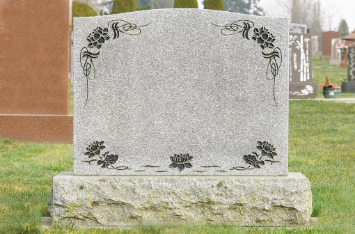 Grey tombstone with flowers in a cemetery.