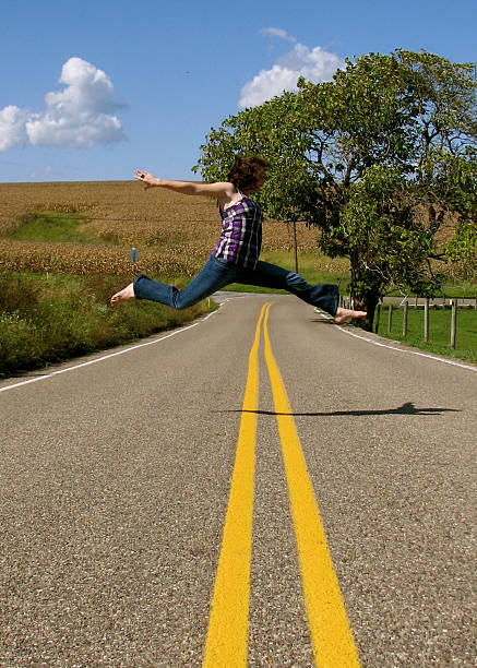 istock Girl doing a dance leap in road 483456220