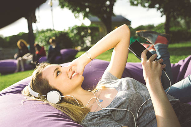 Young Woman At The Park, Listening To Music And Relaxing Young beautiful woman listening to music and relaxing at the park. russian culture audio stock pictures, royalty-free photos & images