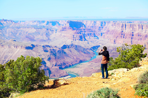 Teen girl taking pictures at the Grand Canyon with cell phone.