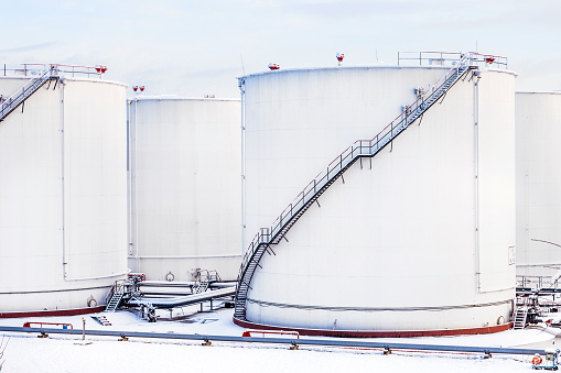 white tanks in tank farm with iron staircase in snow