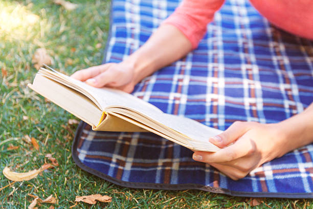 istock Young woman reading book in park 483461264