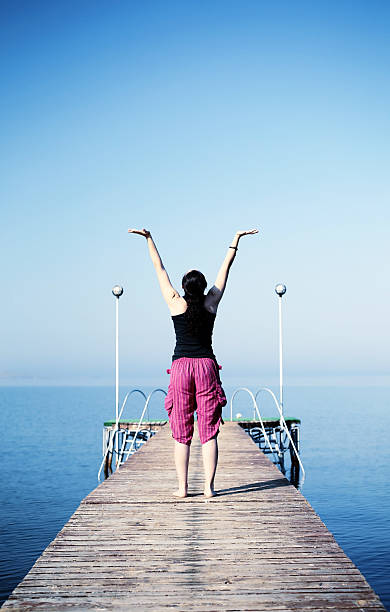 istock Young woman practices yoga on the shore 483465654
